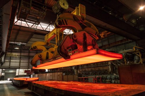 Im Stahlwerk wird eine glühende Stahlbramme verladen